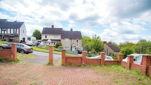 Une rue résidentielle bordée de maisons, avec des voitures garées et un camion de livraison.