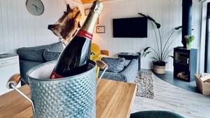Ein gemütliches Wohnzimmer mit Holzboden, einer Couch, einem Fernseher und einer Pflanze.