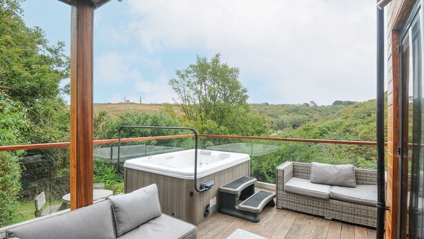 A wooden deck with a hot tub, a sofa, and a small table. - 9 Cedars (St. Agnes)