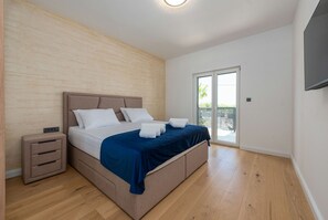 Ein Schlafzimmer mit Bett, Nachttisch und einer Glastür zum Balkon.