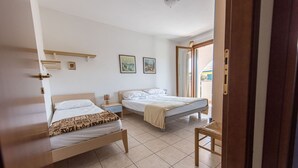 Een slaapkamer met twee bedden, een houten stoel, een nachtkastje en een raam met uitzicht.