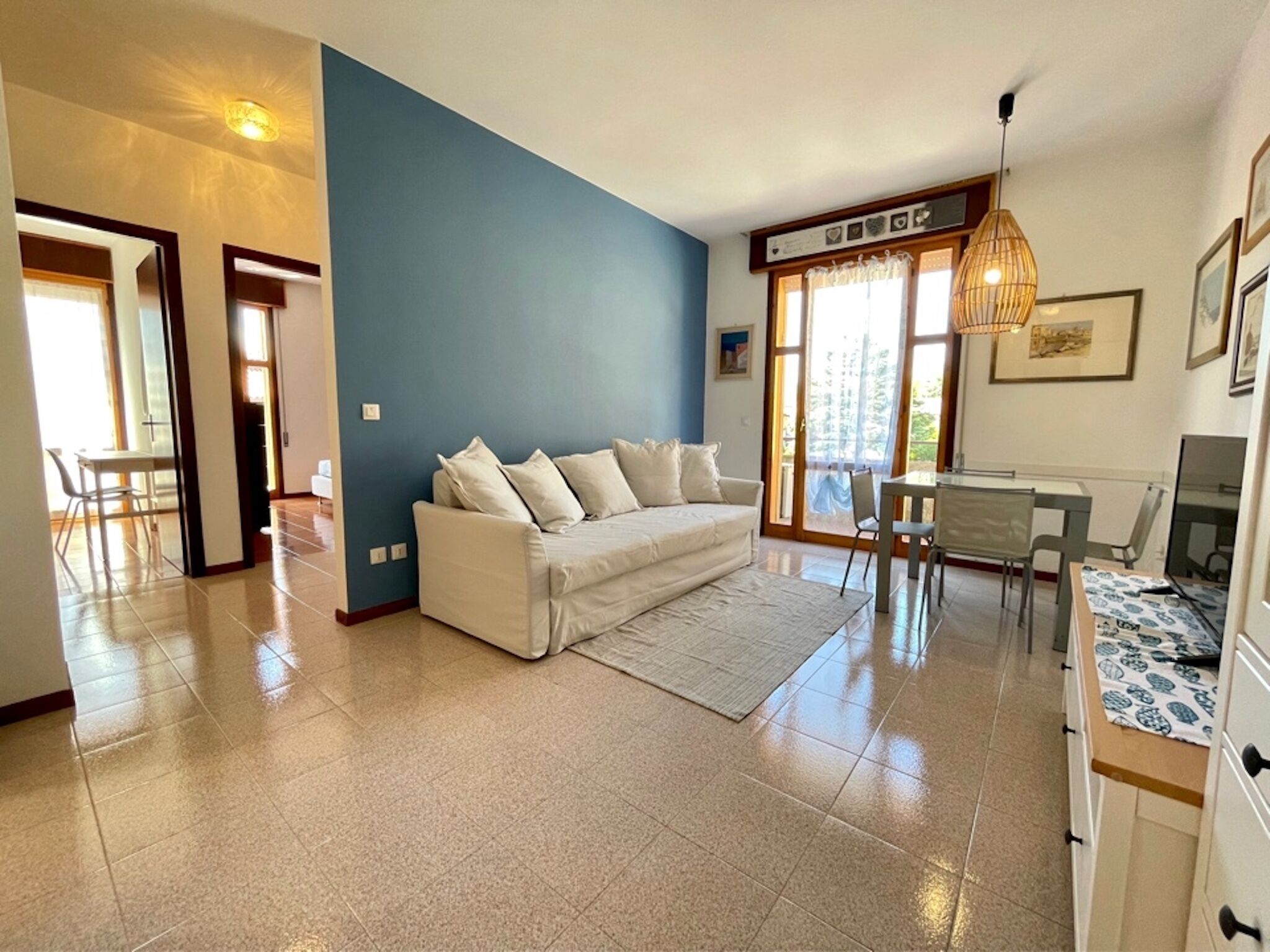A living room with a sofa, a dining table, and a kitchen area.