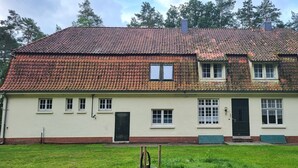 A two-story house with a red-tiled roof, white exterior walls, and a brick foundation. - Spacious vacation home on 19 hectares of woodland in a secluded location (Gerdau)