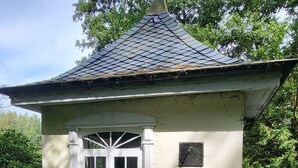 A small, single-story building with a tiled roof and a white door with glass panels. - Spacious vacation home on 19 hectares of woodland in a secluded location (Gerdau)