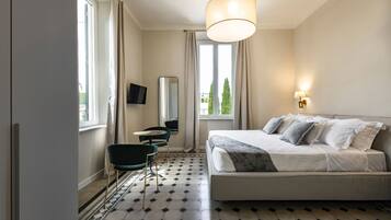 A hotel room with a bed, a desk, a chair, a television, and a window with curtains.