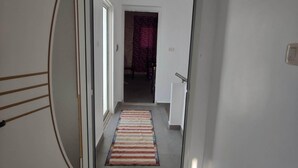 Un pasillo con un tapete a rayas, una puerta con un diseño circular y una pared lisa.