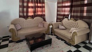 Una sala de estar con dos sofás color beige, una mesa de centro negra y piso a cuadros.