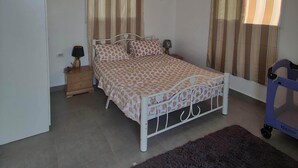 Un dormitorio con cama, mesita de noche, lámpara, cómoda y una silla de ruedas.