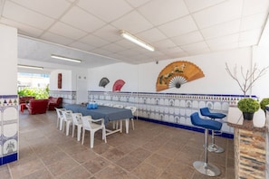 Ein Essbereich mit einem langen Tisch, weißen Stühlen und blauen Barhocker.