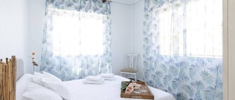 Habitación de hotel con cama, una silla y una bandeja con toallas y una cesta de frutas.