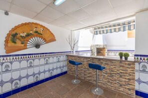 Un coin bar équipé d’un ventilateur, d’un mur carrelé et de deux tabourets.