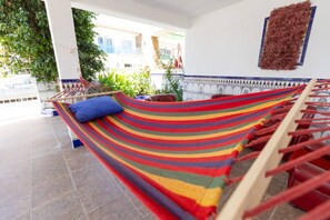 Un hamac en tissu à rayures, un coussin bleu et une structure en bois.
