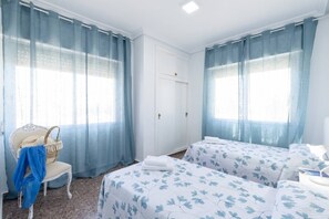 Ein Hotelzimmer mit zwei Betten, einem Sessel und einem Kleiderschrank.