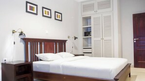 Un dormitorio con una cama de madera, mesitas de noche, un armario y lámparas fijadas a la pared.