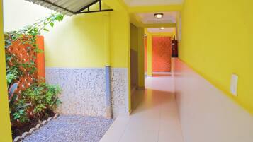 A hallway with yellow walls, a tiled floor, and a door at the end.