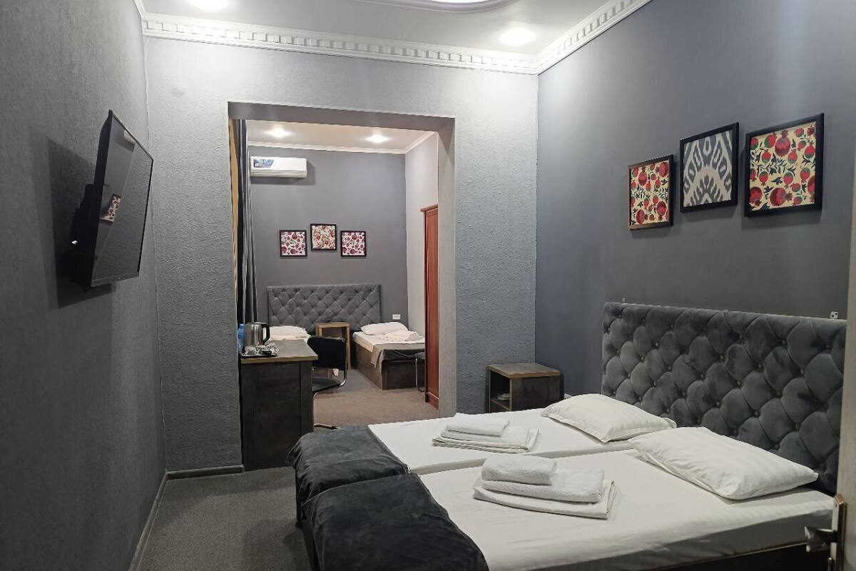 Ein Hotelzimmer mit einem großen Bett, einem Schreibtisch, einem Stuhl, einem kleinen Tisch und einem Fernseher. An der Wand hängen drei gerahmte Bilder.