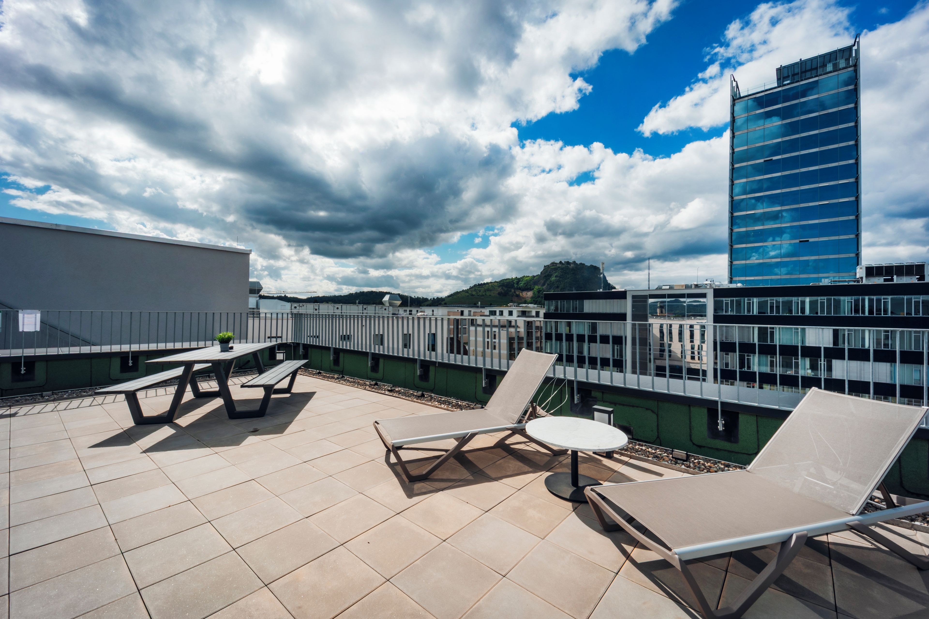 A rooftop terrace with outdoor seating and a view of a cityscape.
