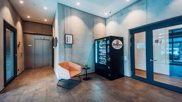 A modern lobby with a vending machine, a seating area, and a glass door leading outside.