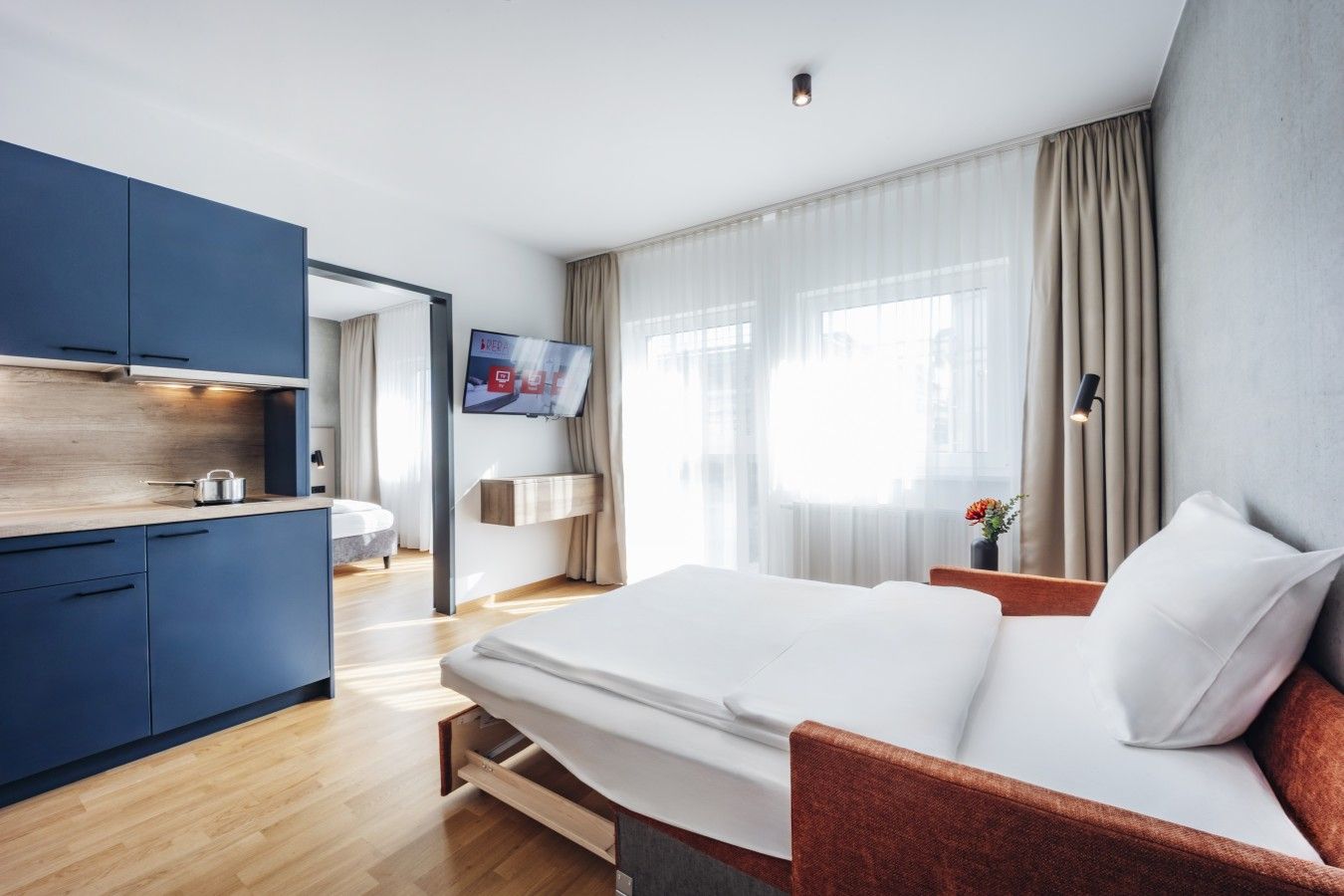 A modern hotel room with a bed, a desk, and a TV.