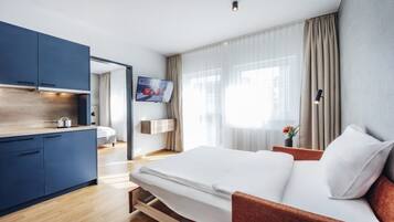 A modern hotel room with a bed, a desk, and a TV.