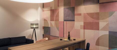 A modern dining area with a wooden table, blue chairs, and a geometric patterned wall.