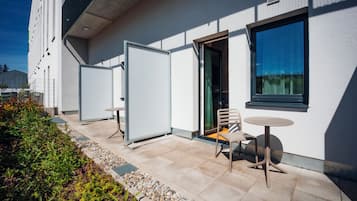 Un área de estar exterior moderna con una mesa, sillas, una puerta y una ventana.
