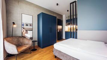 Ein modernes Hotelzimmer mit Bett, Stuhl, Kleiderschrank und Spiegel.