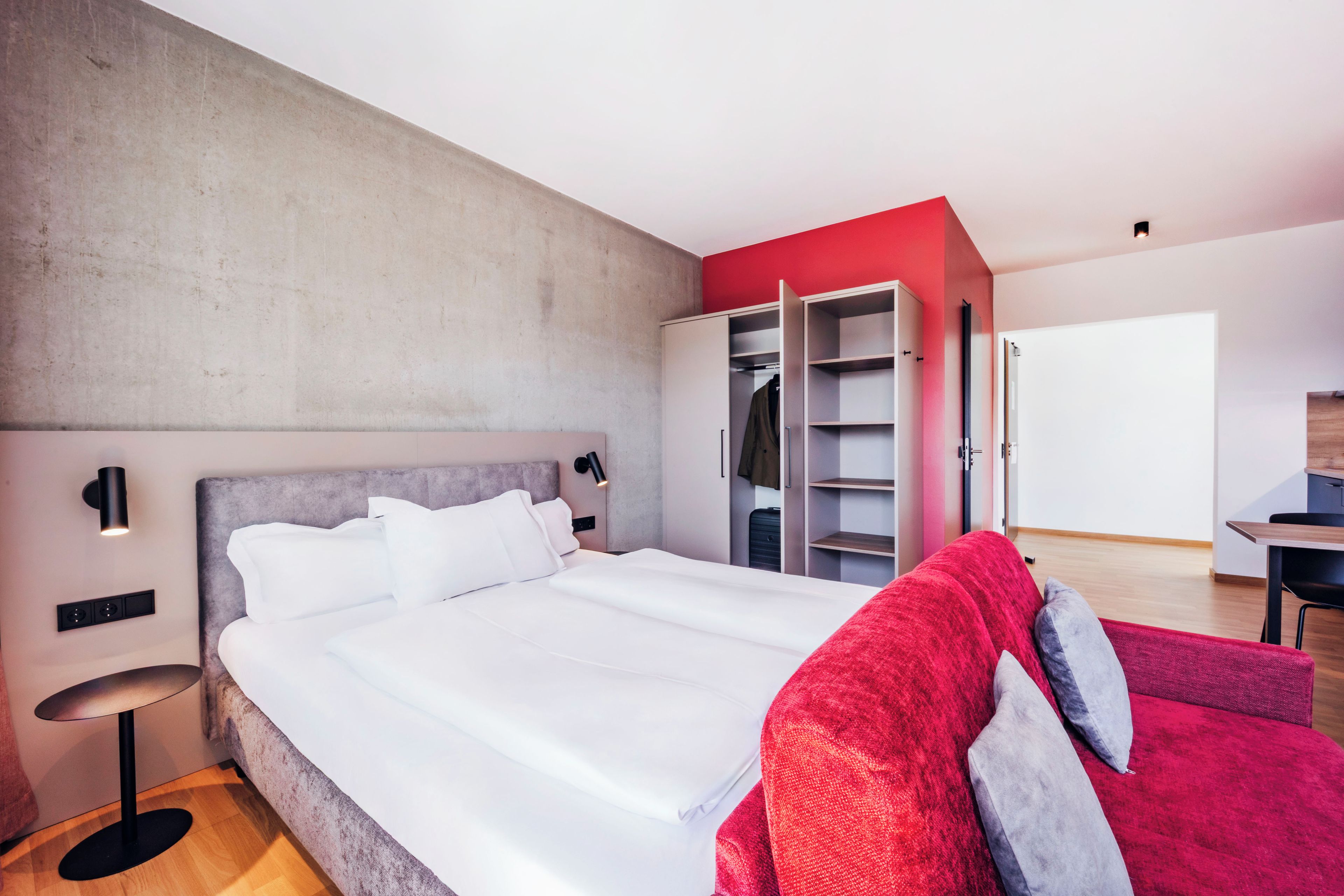 A modern bedroom with a large bed, a wardrobe, and a desk.
