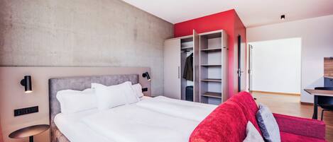 A modern bedroom with a large bed, a wardrobe, and a desk.