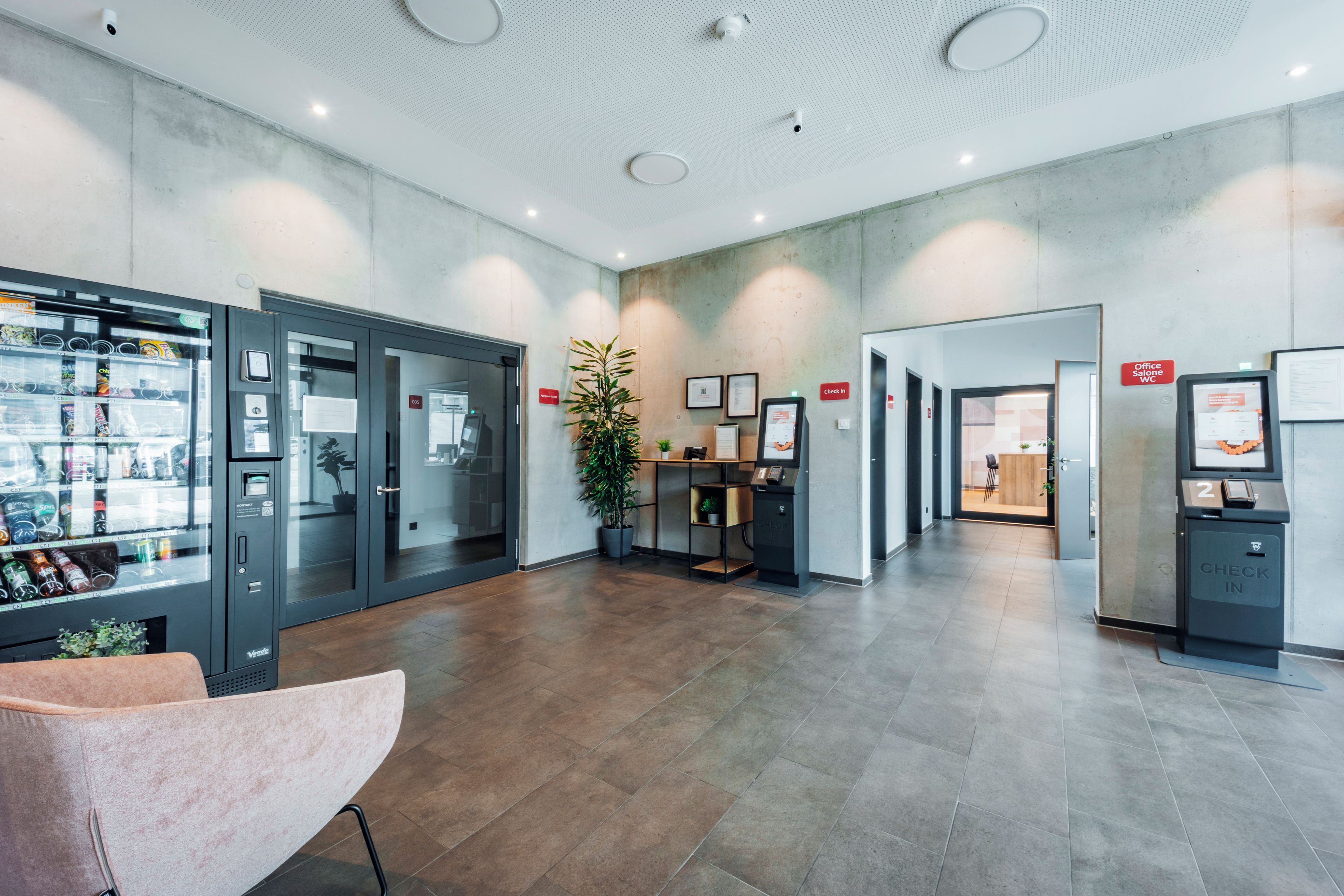 Een moderne receptie met een automaat, een incheckbalie en een zithoek.