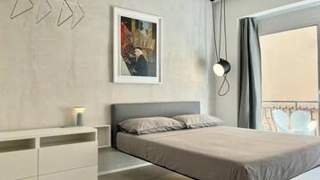 Een moderne slaapkamer met een bed, nachtkastje en een schilderij aan de muur.