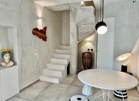 A modern interior with a staircase, a round table, and a bust sculpture.