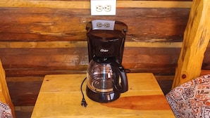 Une table en bois avec une machine à café, une prise de courant et une prise murale.