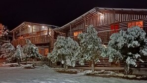 Un chalet en bois, avec un paysage enneigé illuminé par la nuit.