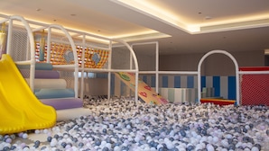 Espaço infantil com piscina de bolinhas, escorregadores e brinquedos macios.