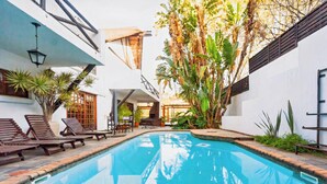 A swimming pool with lounge chairs and a staircase leading to an upper level. - Pretoria Mansion Boutique Hotel (Pretoria)