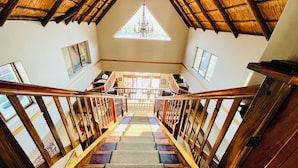 A staircase with wooden railings and a thatched roof, leading to a seating area with tables and chairs. - Pretoria Mansion Boutique Hotel (Pretoria)