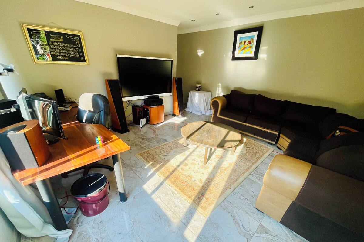 A living room with a flat-screen TV, a wooden coffee table, a sofa, and a patterned rug.