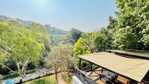 A terrace with a table and chairs, overlooking a lush green landscape with trees and a distant building. - Pretoria Mansion Boutique Hotel (Pretoria)