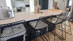 A modern kitchen with a central island, bar stools, and pendant lighting. - Bryn Gwynedd (Conwy)
