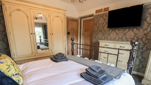 A bedroom with a bed, a wardrobe, a dresser, and a television on the wall. - Bryn Gwynedd (Conwy)