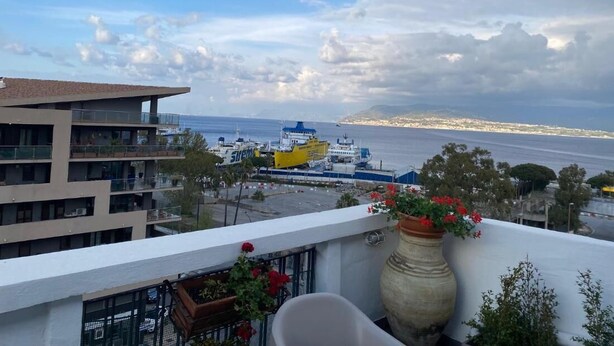A balcony with a view of the sea, a yellow and white ship, and a distant coastline. - Casa Malù----------- (Messina)