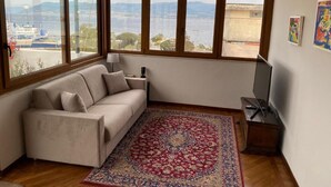 A room with a sofa, a rug, and a TV. - Casa Malù----------- (Messina)