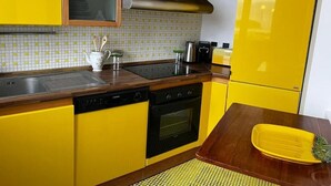 A kitchen with yellow cabinets, a stainless steel range hood, a dishwasher, and an oven. - Casa Malù----------- (Messina)