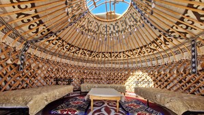 A yurt with a central table, two benches, and a patterned floor. - Agat Yurt Camp (Kaji-Say)