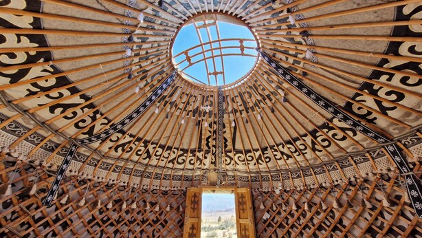 A traditional yurt with a circular wooden frame, patterned fabric, and a central opening. - Agat Yurt Camp (Kaji-Say)