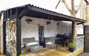 Relax in a serene outdoor space with a pergola, wicker furniture, and a glass-top table.