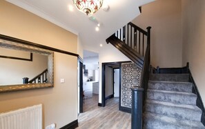 Staircase leads to an upper floor, featuring a decorative mirror and patterned wall panel.