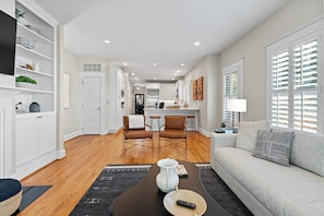 A modern living room with a sofa, a coffee table, and a dining area with chairs. - 402 House in Heart Historic Old Town, Walk to King St, Water, Shops, Metro & DMV (Alexandria)