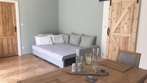 Ein Zimmer mit einem Bett, einem Schlafsofa, einem Holztisch mit Tablett und einer Stallschürze.